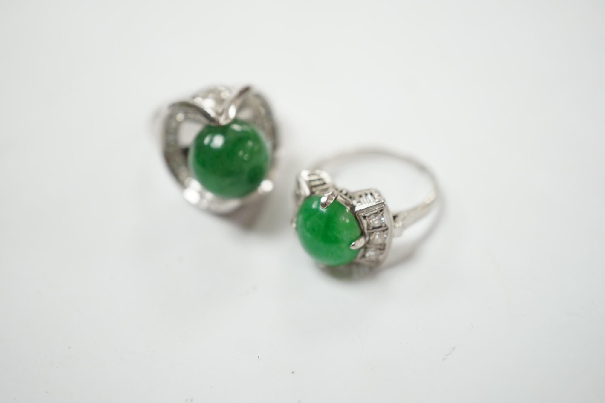 A modern white metal (stamped Pt) and jade bead set ring, with diamond set shoulders, size J/K, together with a similar larger white metal jade bead and diamond set ring, size I/J, gross weight 19.9 grams. Condition - fa